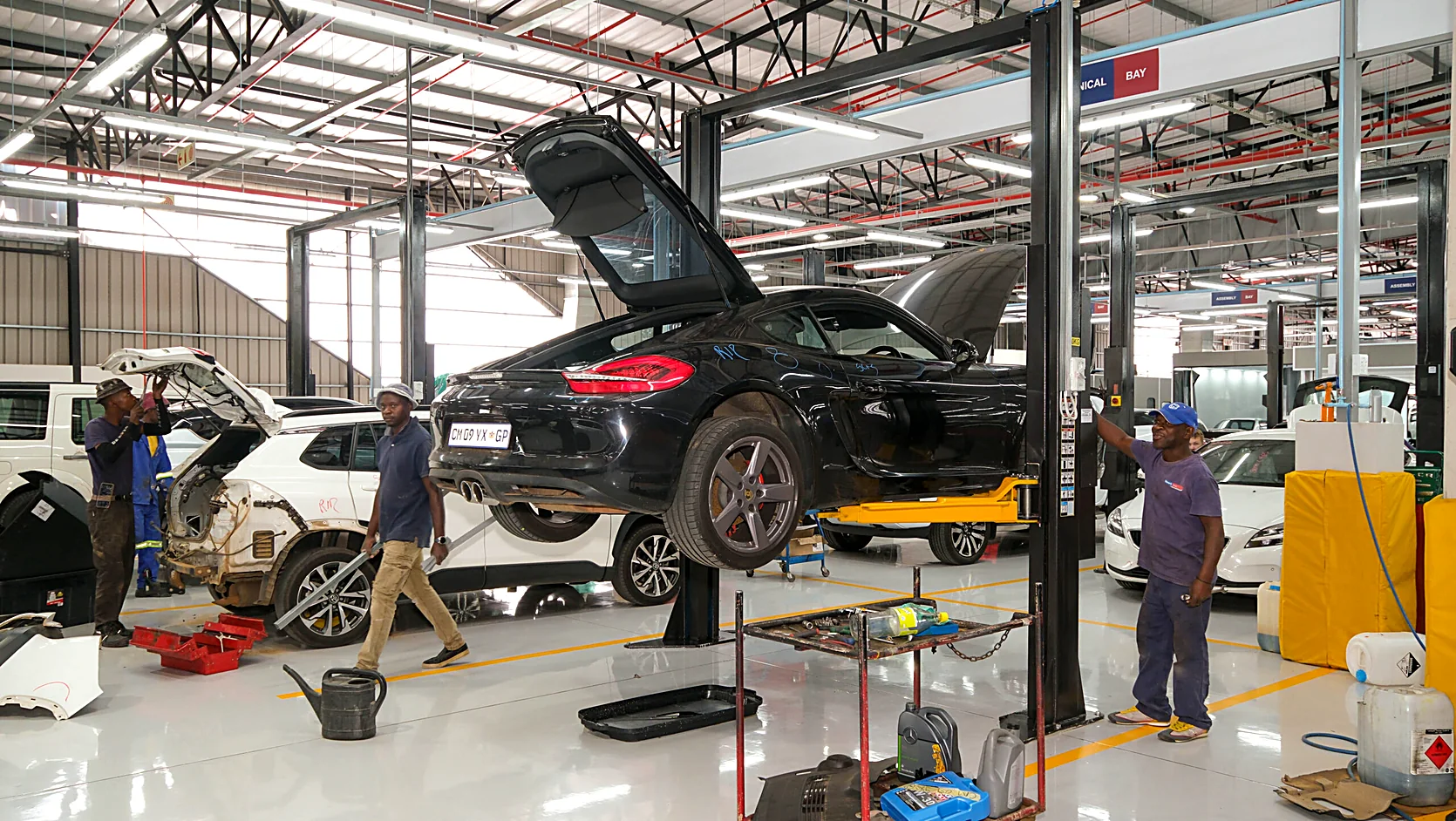 Premium autobody workshop with a vehicle undergoing panel inspection by a Renew-it technician