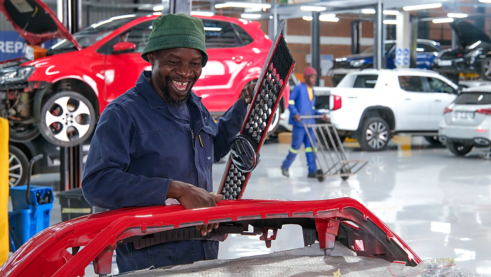 Technician performing panel beating repair work on a dented vehicle body panel