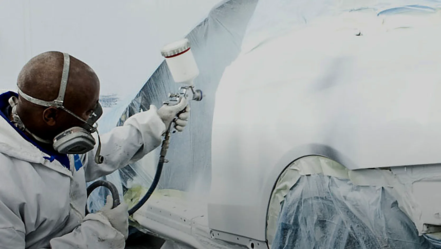 Vehicle masked and prepared for refinishing in a controlled spray painting booth